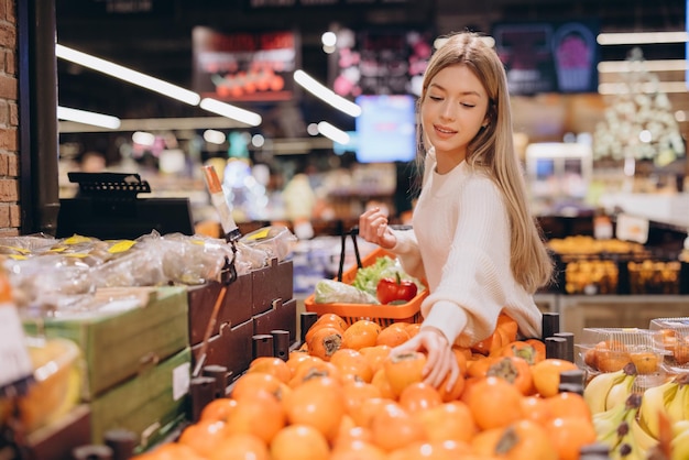 Woman choosing fresh persimmon fruit at the supermarket