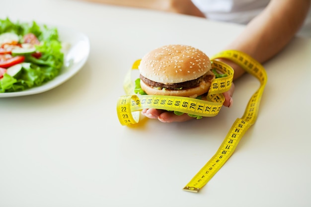 Woman choosing between junk burger and fresh salad