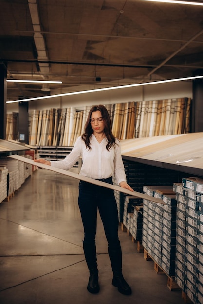 woman choosing laminate floor design from samples in flooring store