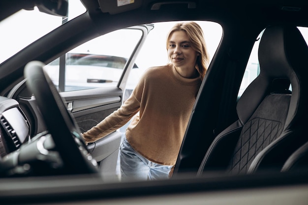 Woman choosing new car in car showroom