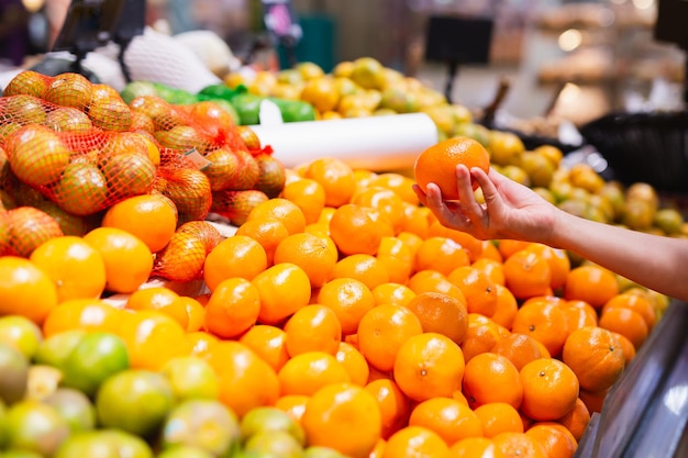 Woman choosing oranges in grocery store Concept of healthy food