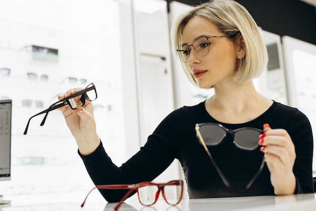 Woman choosing a pair of eyeglasses at optics store