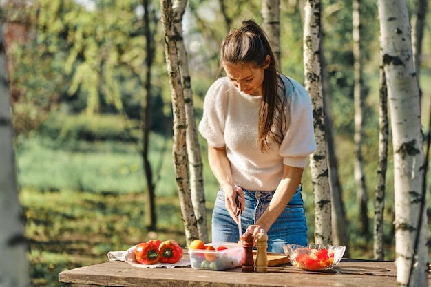 Woman chopping bell pepper for salad on backyard