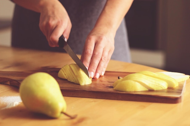 woman chopping pear with knife on cutting board