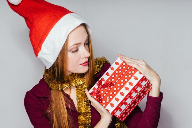 Woman in a Christmas hat holds a gift in her hands