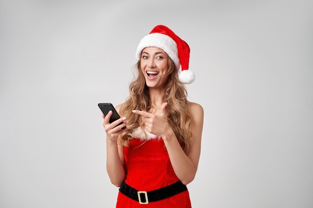 Woman christmas Santa Hat white studio background with smartphone in hand