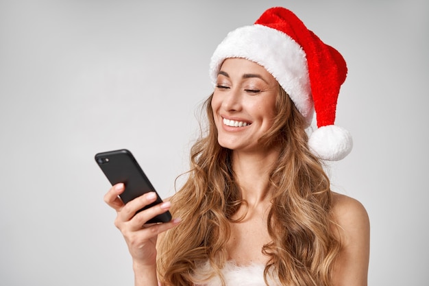 스마트폰 손에 여자 크리스마스 산타 모자 흰색 스튜디오 배경
