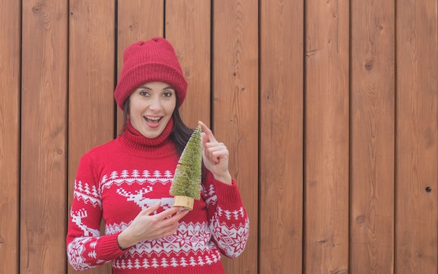 Женщина в рождественском свитере держит подарок