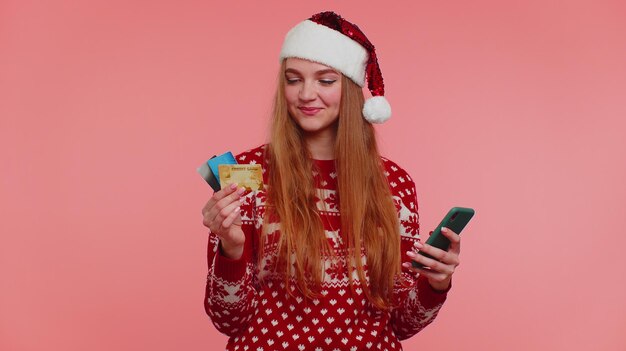 Woman in christmas sweater use mobile cell phone and plastic credit bank card win calebrate wow