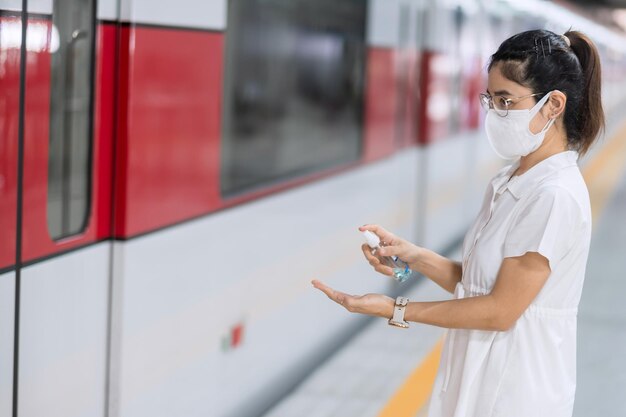 Donna pulita a mano con gel igienizzante alcolico in treno o nei trasporti pubblici, protezione contro l'infezione da malattia di coronavirus. igiene personale, sicurezza e trasporto di viaggio secondo i concetti di covid-19