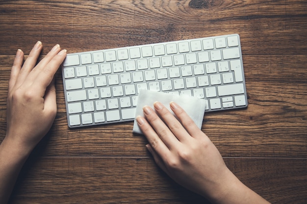 Woman clean keyboard in napkin on the desk