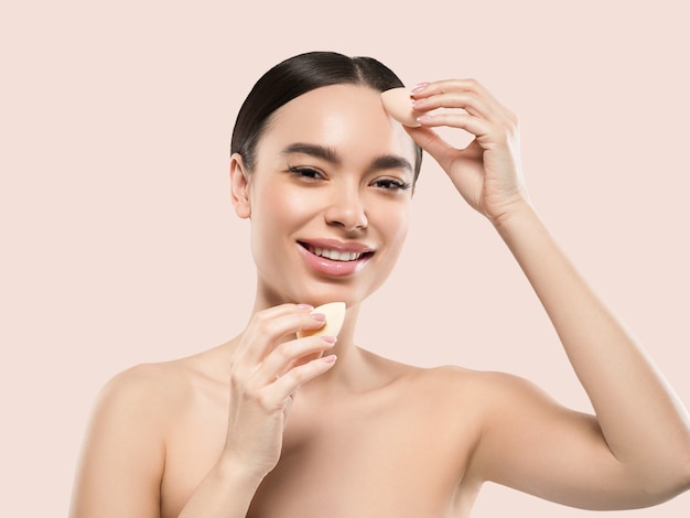 Woman clean skin with sponge beauty healthy skin beauty. Color background. Pink