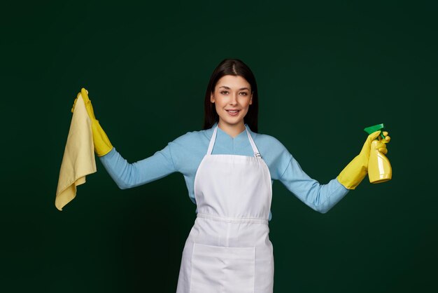 Woman in cleaner apron wieaning rag and detergent sprayer