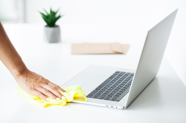 Woman cleaner tidies up the computer desk in the office