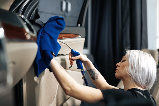 写真 オートディテーリングサービスで研磨スプレーでカーサロンを掃除する女性
