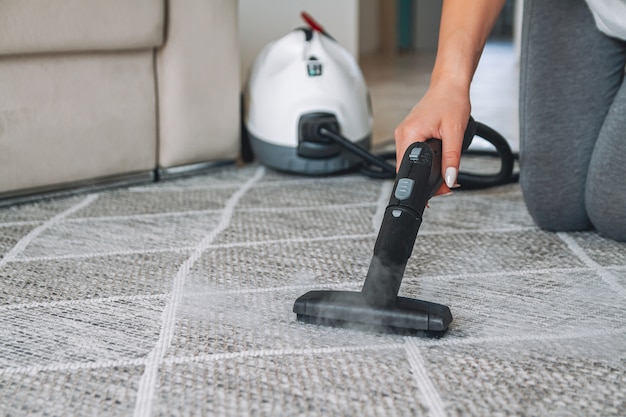 Woman cleaning carpet with a steam cleaner