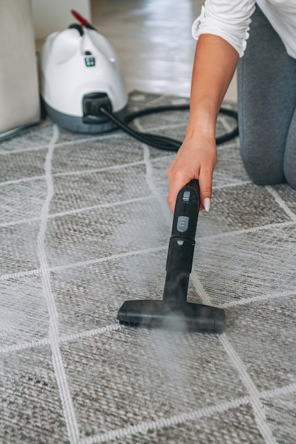 Woman cleaning carpet with a steam cleaner