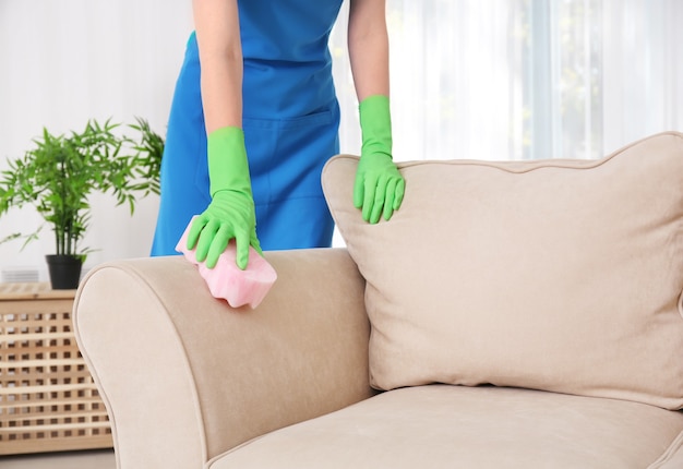 Woman cleaning couch with sponge at home