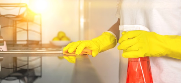 Женщина чистит прилавок, баннер, фото на домашней кухне, рука в резиновой перчатке с распылителем и кухонной тряпкой