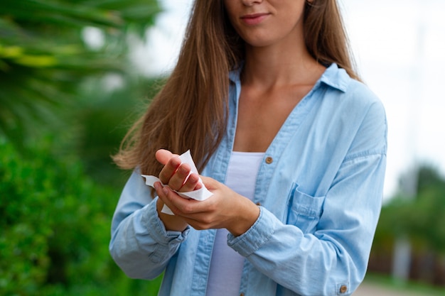 Woman cleaning and disinfection hands with antibacterial wet wipes outdoors