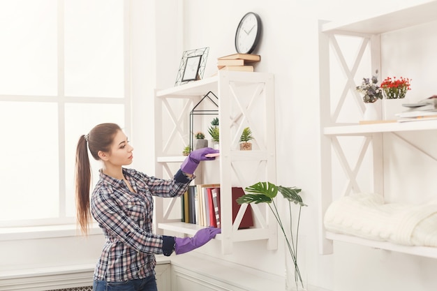 Foto donna che pulisce la polvere dalla libreria