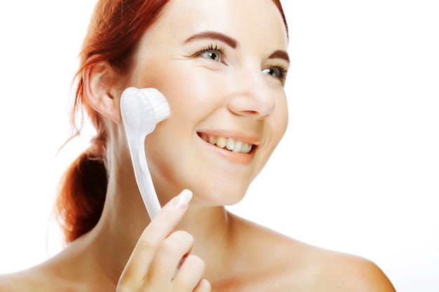 woman cleaning face with peeling brush