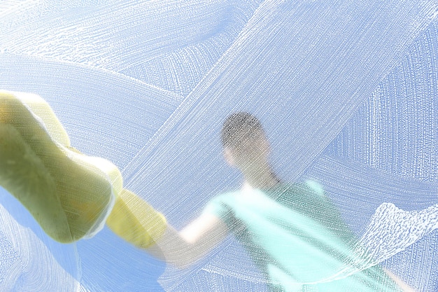 Woman cleaning glass with sponge on sunny day