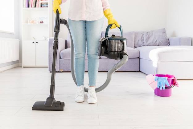 Женщина убирает свой дом пылесосом