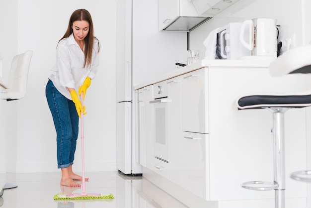 Foto donna che pulisce la cucina con una vista lunga di zazzera