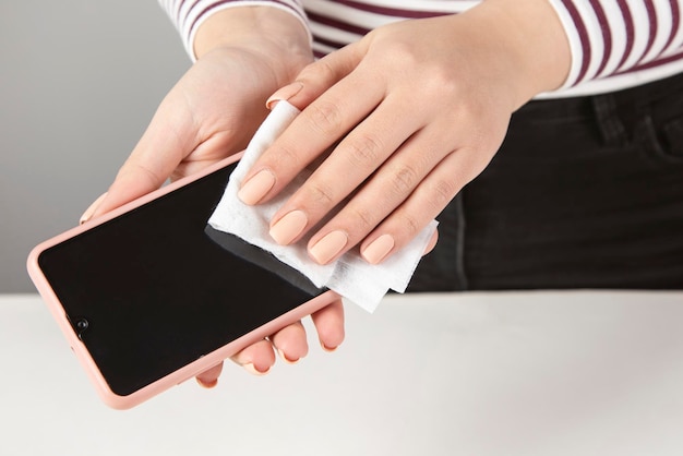 Woman cleaning phone with antiseptic wipe