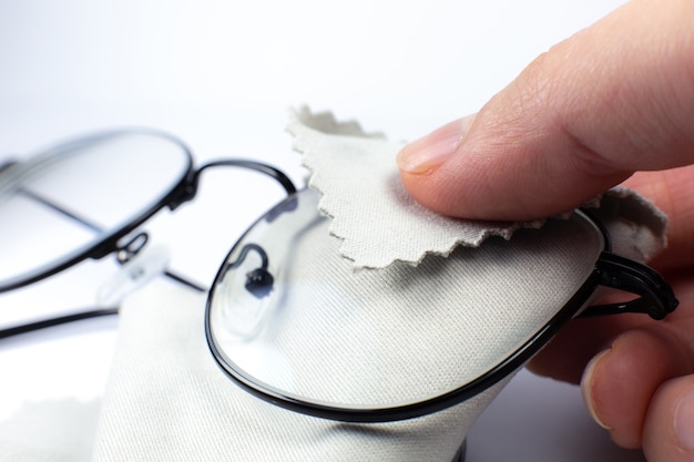 Woman cleaning reading glasses with cloth. Close up photo.