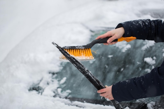 冬に車から雪を掃除する女性