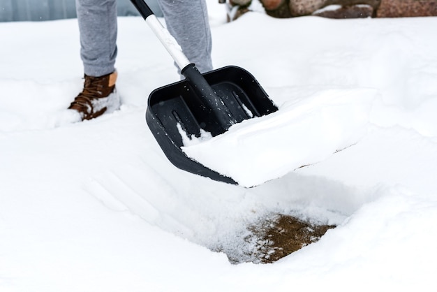 Woman cleaning snow from sidewalk and using snow shovel.