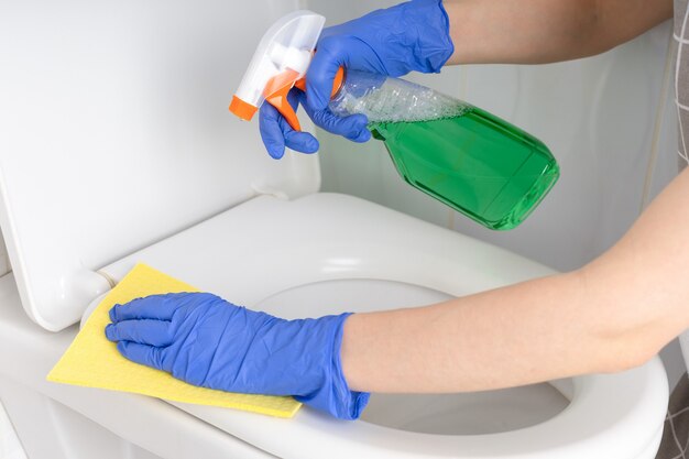 Woman cleaning toilet bowl in bathroom close up