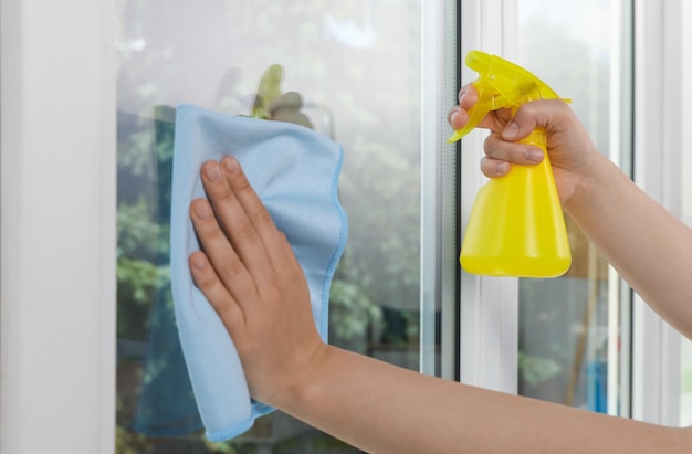 Photo woman cleaning window glass with rag and spray indoors closeup