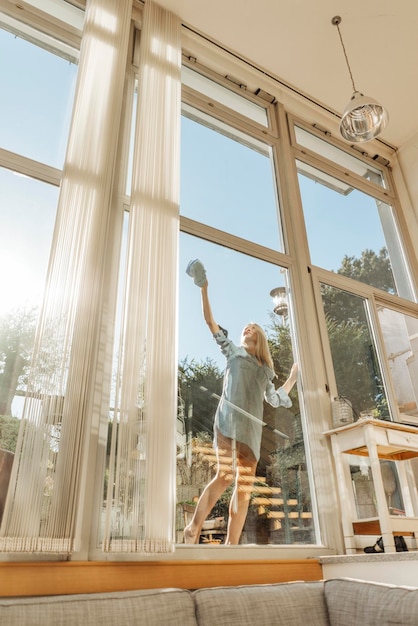 Woman cleaning the window in sunshine