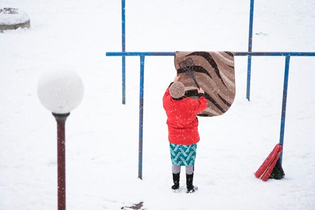 Photo a woman cleans the carpet in winter