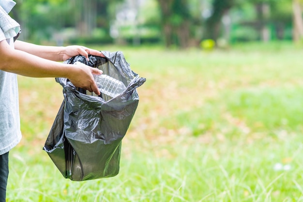 Foto donna pulisce raccogliendo bottiglie di plastica in giardino concept di protezione dell'ambiente risparmio del mondo riciclaggio riduzione del riscaldamento globale close up sfondo sfocato spazio di copia a destra