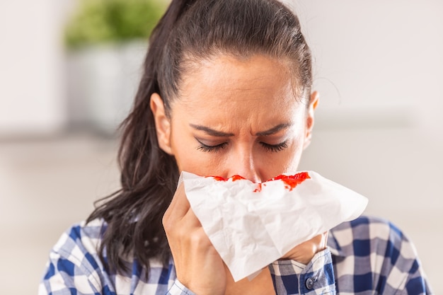 Woman clears her nose, unaware of bleeding that appeared on a tissue.