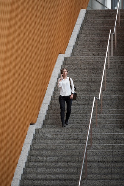 Foto donna che scende le scale colpo lungo