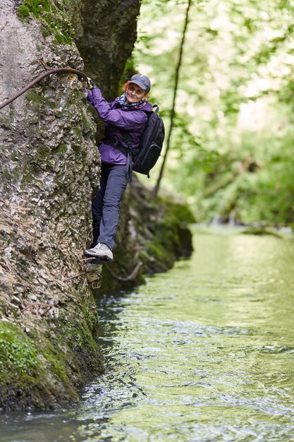 Woman climbing on a mountain wall over a river in a canyon