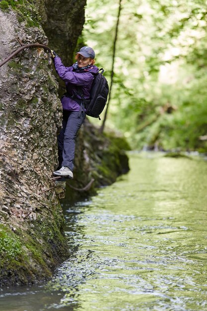 Woman climbing on a mountain wall over a river in a canyon