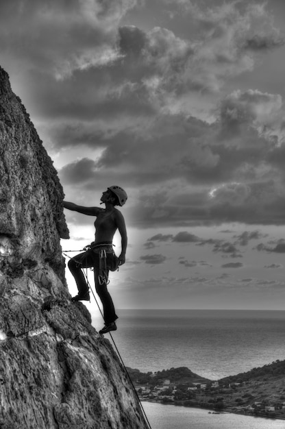 Foto donna che si arrampica sulla roccia contro il cielo