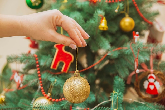 Woman clings a Christmas toy on a Christmas tree