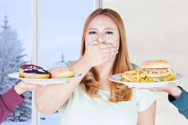 写真 不健康な食べ物のために口を閉じた女性