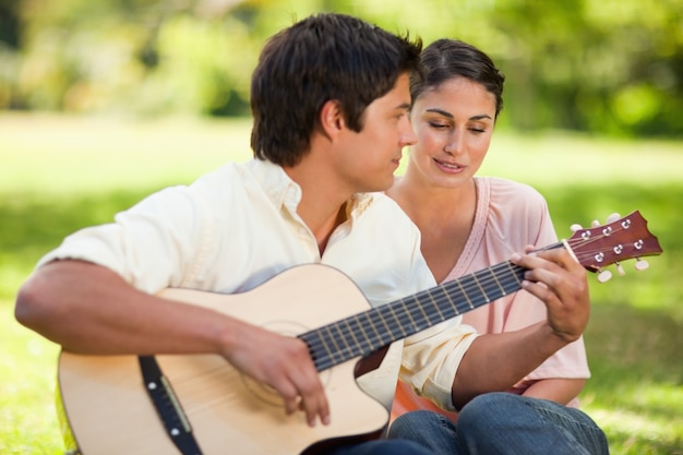 Woman closes her eyes while listening to her friend play the guitar