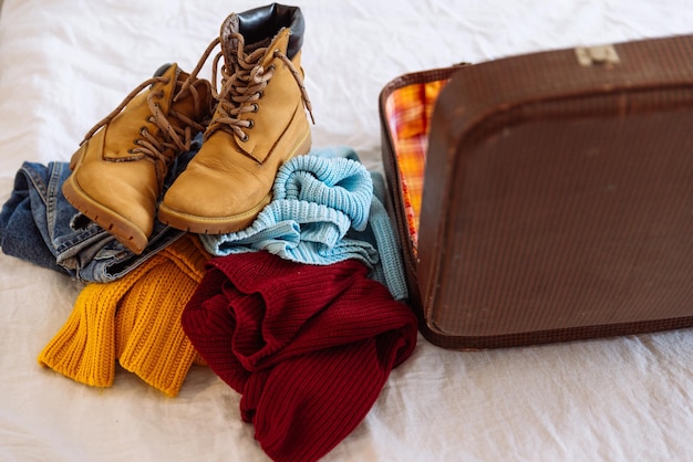 Woman clothes near old vintage suitcase. travel concept. preparing for winter trip