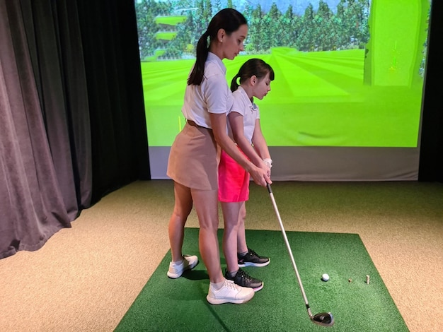 Photo woman coach teaches a child girl to play golf golf lessons