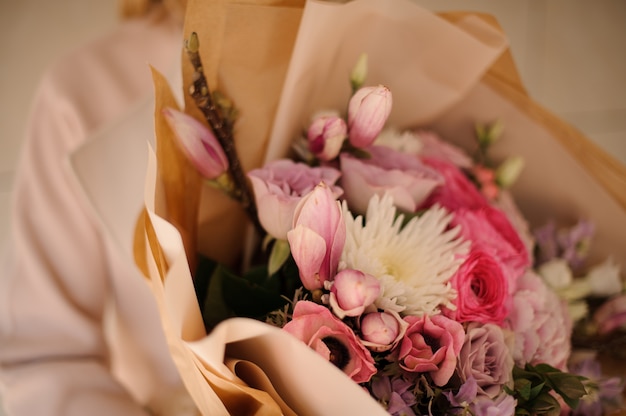 Donna nel cappotto che tiene un mazzo di fiori teneri di colore rosa