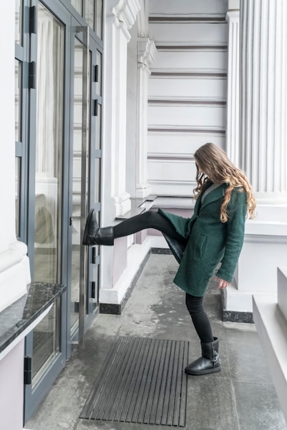 Donna in cappotto dà un calcio alla porta chiusa